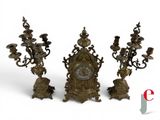 three candlesticks and a clock on a white background