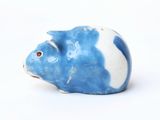 a small blue and white pig figurine on a white surface