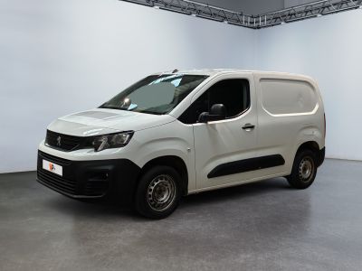 La camionnette blanche est garée dans une grande pièce aux murs blancs.