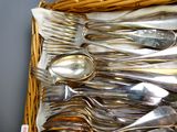 de nombreuses cuillères et fourchettes dans un panier en osier