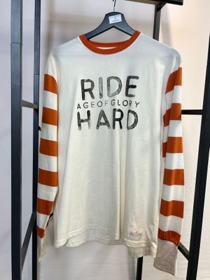 Une chemise blanche à rayures orange et blanches est suspendue à un portant.