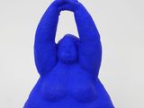 blue sculpture of a man sitting on his back with his hands in the air