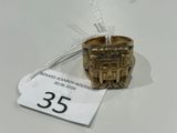 une bague en or ornée d'un château, posée sur une table