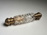 a small glass bottle with a gold handle on a white surface