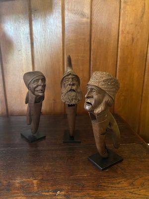trois figurines en bois posées sur une étagère en bois dans une pièce