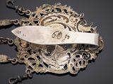 a silver brooch with a knife on top of it