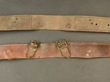 two belts with metal buckles on them on a gray surface