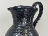 a black vase with a gold design on it