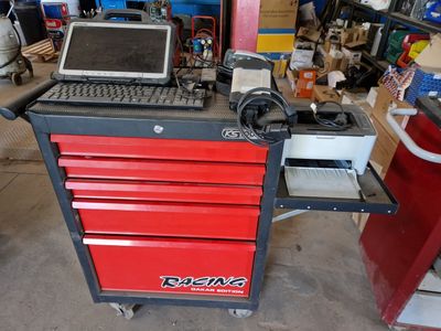 a laptop computer sitting on top of a red tool cabinet