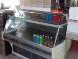 un comptoir réfrigéré dans un restaurant, avec des sodas posés dessus