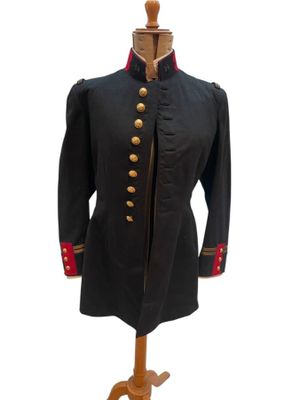 un manteau militaire noir à boutons rouges posé sur un présentoir pour mannequin