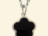 un gros plan d'un pendentif en forme de fleur noire monté sur une chaîne en argent