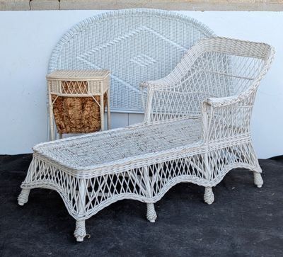 a white wicker bench and a wicker chair on the ground