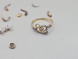 a gold and silver ring on a table with other gold and silver rings