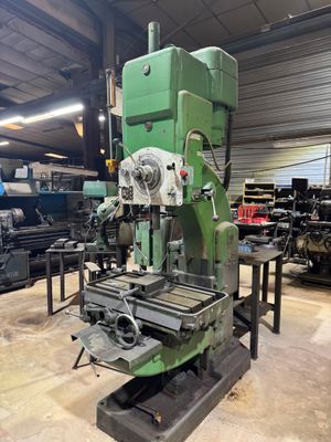 une photo représentant une machine dans un atelier, avec d'autres machines en arrière-plan