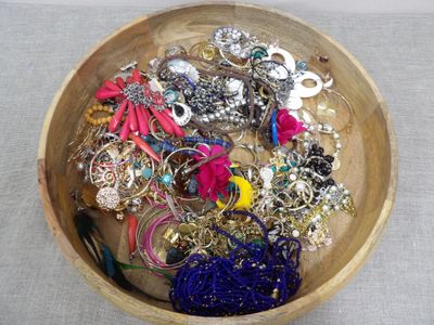 a wooden bowl filled with assorted jewelry on a table