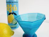 a blue glass bowl next to a lemon and a can of soda