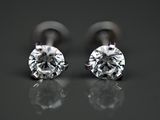 une paire de boucles d'oreilles en diamant posée sur une surface réfléchissante