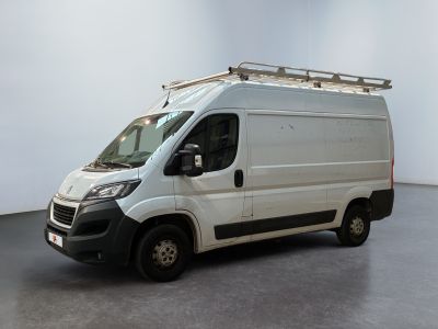 La camionnette blanche est garée dans une grande pièce au sol noir.