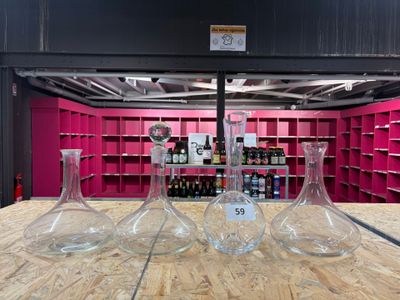 trois vases posés sur une table devant une étagère remplie de bouteilles