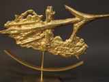a gold sculpture of a fish on a stand