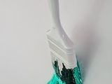 a close up of a brush with green paint on it on a white surface