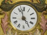 a gold clock with a white face and a bird on it