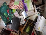 a pile of books on a bed next to a book case