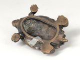 an image of a small bronze turtle with a stone in its shell