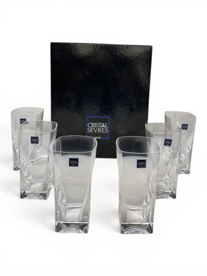 six crystal shot glasses in front of a black box on a white surface