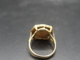 gros plan d'une bague en or sur une surface noire