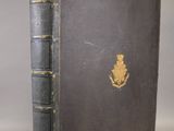 an old black book with a gold emblem on the cover