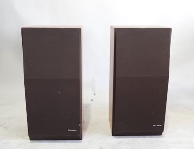 two speakers sitting on top of a white surface next to each other