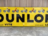yellow and black dunlop sign on concrete floor next to wall