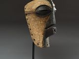a wooden mask on a stand on a white surface