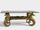a gold coffee table with a glass top and two seahorses on it