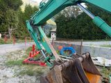 a green excavator that is sitting on the side of the road