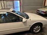 a white car parked in a garage next to another car