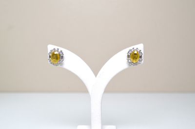 paire de boucles d'oreilles à clous en saphir jaune et diamants, présentées sur un socle blanc