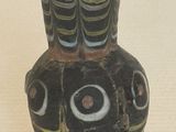 un vase noir orné d'un motif, posé sur une table