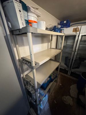 a refrigerator and shelves in a room with a lot of stuff