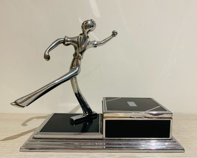 statue of a man holding a tennis racquet on top of a wooden table