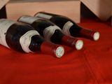 several bottles of wine are lined up on a red table cloth