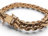 a close up of a gold bracelet on a white background