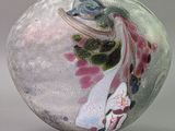 a glass vase with a bird on it on a table