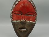 un gros plan d'un masque en bois au visage rouge