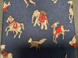 a close up of a blue tie with horses and dogs on it
