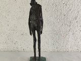 statue of a man standing on a base with a white wall in the background