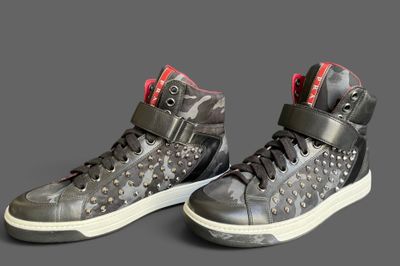 pair of black and red high top sneakers on a grey background