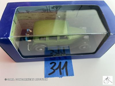 une petite voiture verte dans une boîte bleue posée sur une table blanche